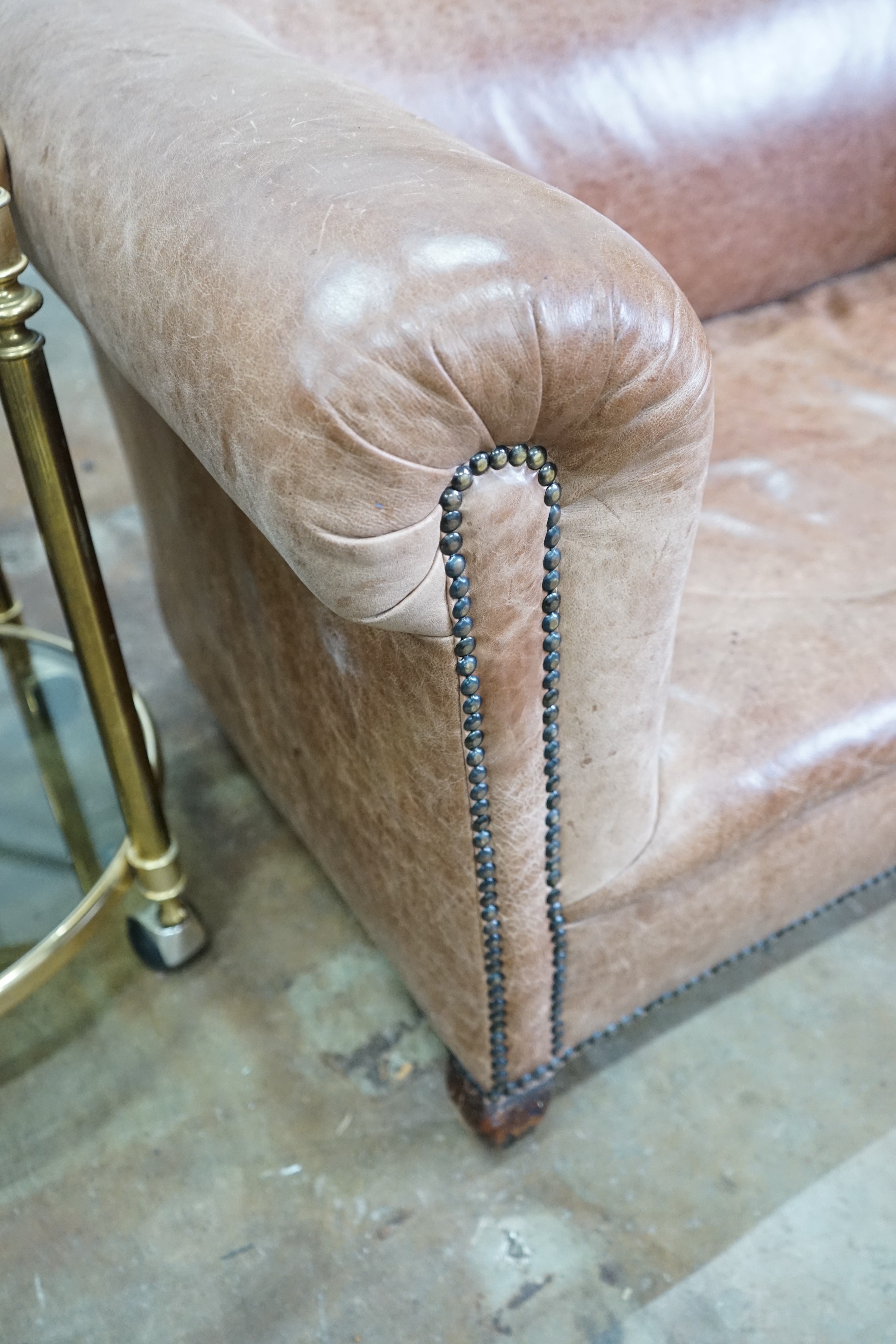 An early 20th century tan leather drop arm Chesterfield settee, width 160cms, depth 84cms, height 69cms.